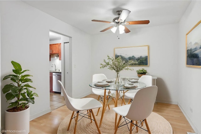 dining space featuring sink, ceiling fan, and light wood-type flooring