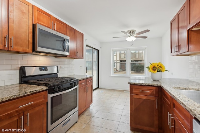 kitchen featuring light stone counters, light tile patterned floors, ceiling fan, stainless steel appliances, and backsplash