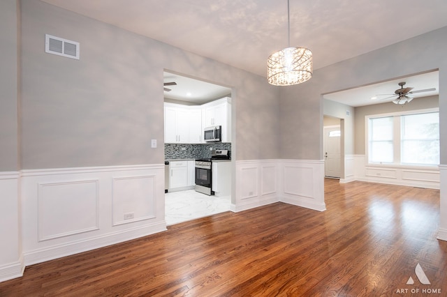 interior space featuring ceiling fan with notable chandelier and wood-type flooring