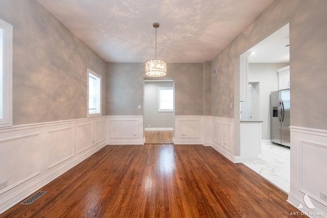 unfurnished dining area featuring a chandelier and hardwood / wood-style floors