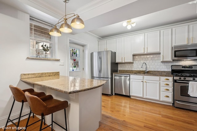 kitchen with a sink, tasteful backsplash, appliances with stainless steel finishes, and crown molding