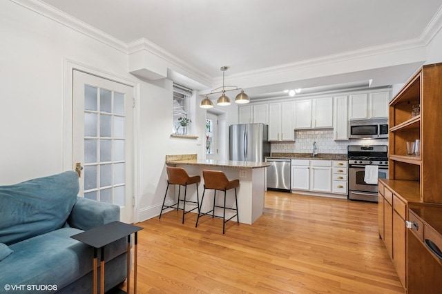 kitchen featuring stainless steel appliances, a peninsula, a breakfast bar area, and light wood finished floors