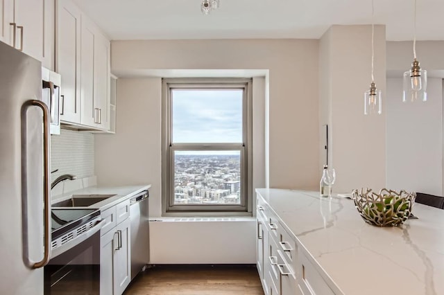 kitchen featuring white cabinetry, appliances with stainless steel finishes, light stone countertops, and sink