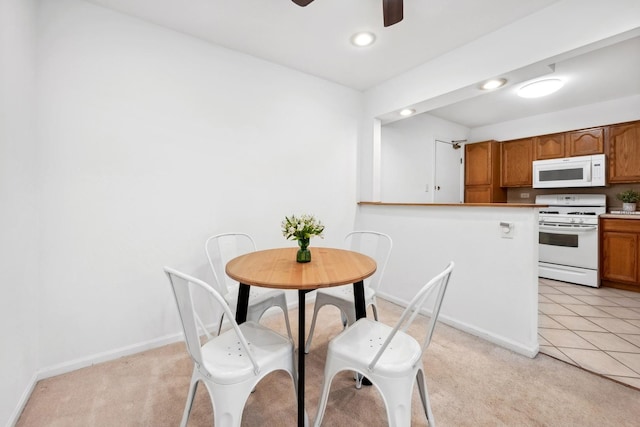 dining space featuring light carpet and ceiling fan