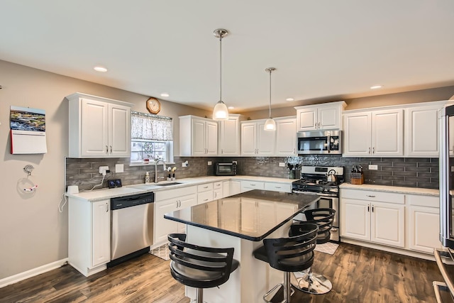 kitchen with a kitchen island, white cabinets, stainless steel appliances, and pendant lighting