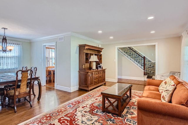 living room featuring an inviting chandelier, hardwood / wood-style floors, and crown molding