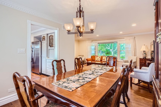 dining room featuring crown molding, a chandelier, and light hardwood / wood-style flooring