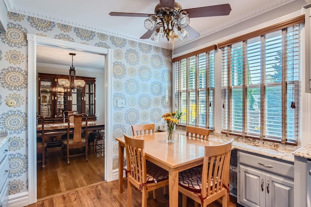 dining area featuring hardwood / wood-style flooring, crown molding, and ceiling fan with notable chandelier