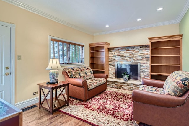 living room featuring hardwood / wood-style flooring, ornamental molding, and a stone fireplace