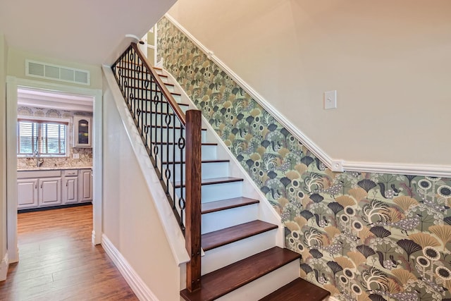 staircase with hardwood / wood-style flooring and sink