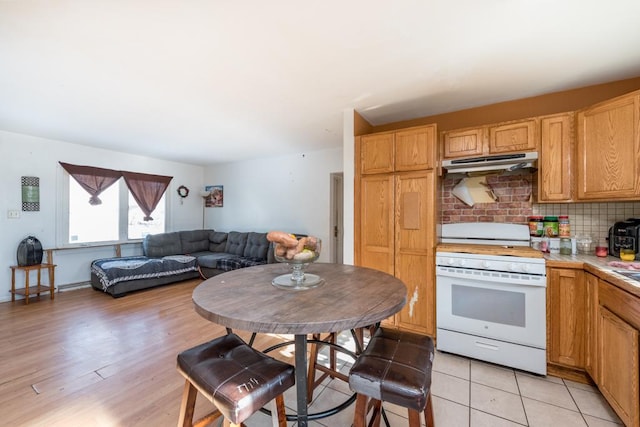 kitchen with tasteful backsplash, white gas stove, and light wood-type flooring