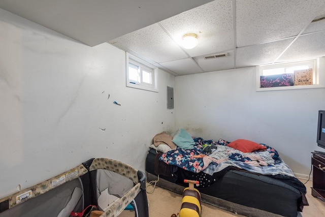 bedroom with a drop ceiling and electric panel