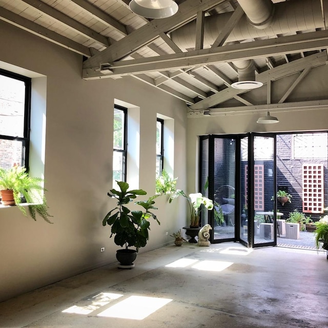 interior space with beam ceiling and concrete flooring