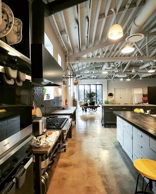 kitchen with white cabinetry, wall oven, and wall chimney exhaust hood