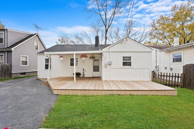 back of house with a wooden deck and a lawn