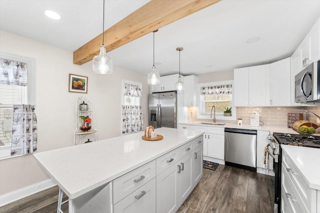 kitchen featuring pendant lighting, sink, appliances with stainless steel finishes, a center island, and white cabinets