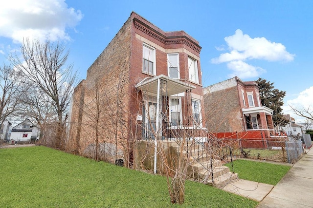 view of front of house featuring brick siding, fence, and a front lawn