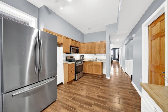 kitchen with light countertops, a sink, wood tiled floor, stainless steel appliances, and baseboards