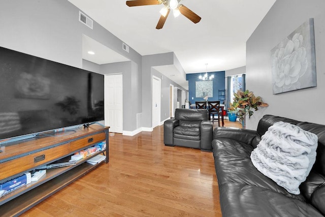 living area with visible vents, ceiling fan with notable chandelier, baseboards, and wood finished floors