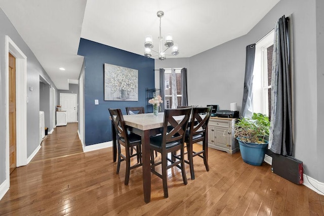 dining room featuring light wood-style floors, a notable chandelier, baseboards, and a wealth of natural light