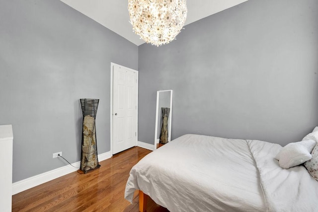 bedroom with baseboards, a chandelier, and wood finished floors
