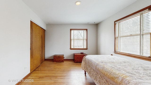 bedroom featuring light wood-type flooring, baseboards, and a closet