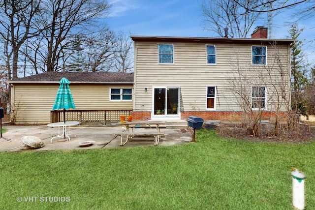 rear view of property with a patio area, a lawn, a chimney, and brick siding