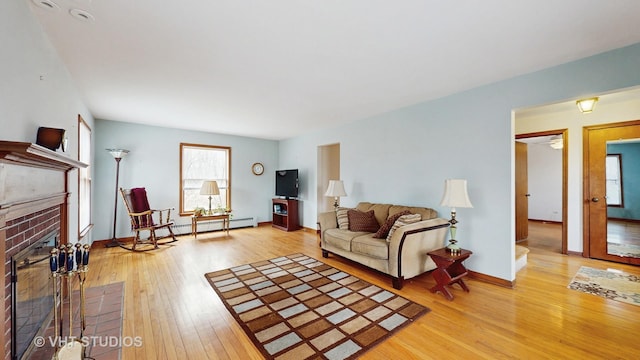 living room featuring a fireplace, baseboards, and wood finished floors