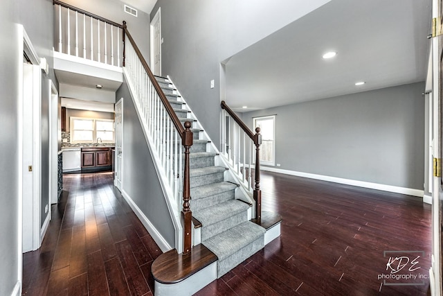 stairs featuring a high ceiling, wood-type flooring, and sink