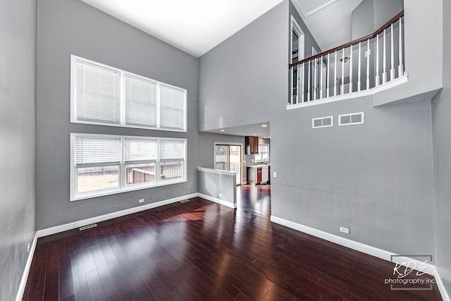 unfurnished living room with hardwood / wood-style floors, plenty of natural light, and a high ceiling