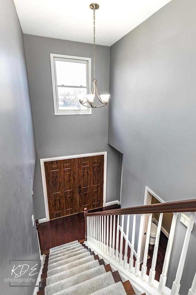 stairway with hardwood / wood-style flooring and a chandelier