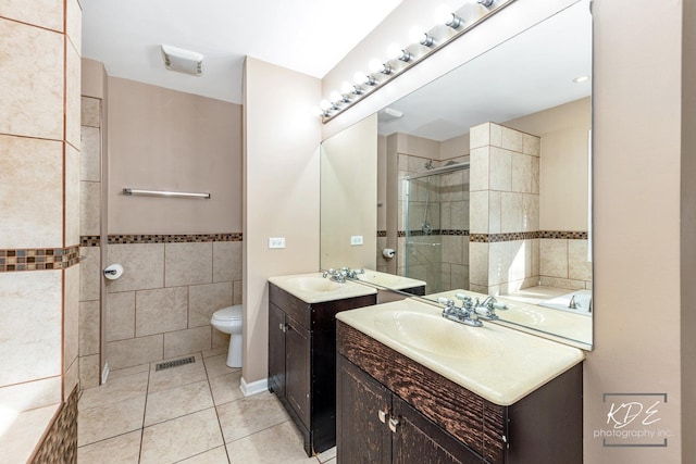 bathroom featuring tile walls, tile patterned flooring, vanity, toilet, and a shower with door