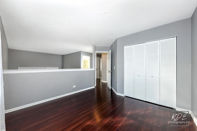 unfurnished bedroom with dark hardwood / wood-style flooring and a closet