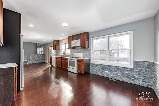 kitchen featuring tasteful backsplash, white appliances, dark hardwood / wood-style flooring, and sink