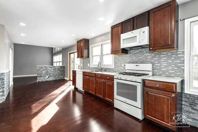 kitchen with white appliances, dark hardwood / wood-style flooring, sink, and backsplash