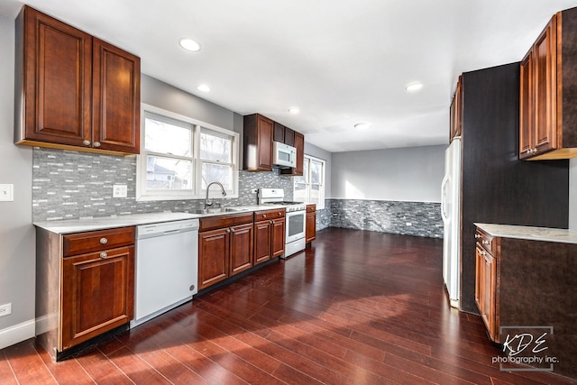 kitchen with sink, white appliances, dark wood-type flooring, and decorative backsplash