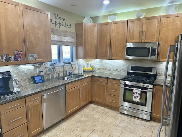 kitchen featuring sink, tasteful backsplash, light tile patterned floors, appliances with stainless steel finishes, and dark stone counters