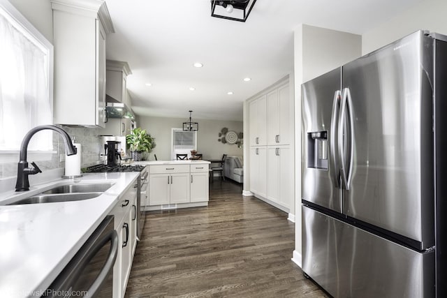 kitchen with sink, appliances with stainless steel finishes, dark hardwood / wood-style floors, pendant lighting, and decorative backsplash