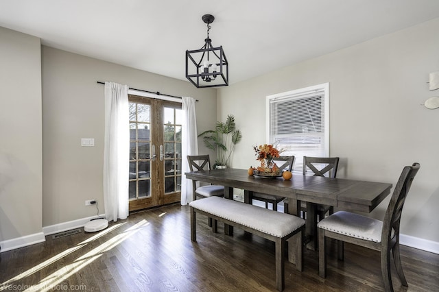 dining room with dark wood-type flooring and an inviting chandelier