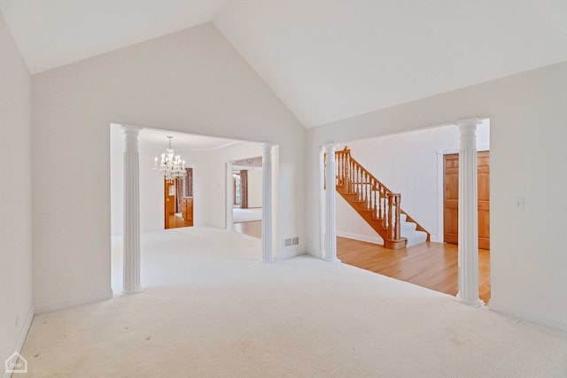 empty room with a notable chandelier, carpet flooring, high vaulted ceiling, and ornate columns