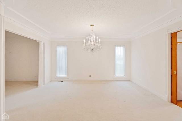 carpeted spare room with an inviting chandelier, ornamental molding, decorative columns, and a textured ceiling