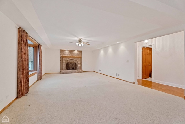 unfurnished living room featuring light carpet, a fireplace, and ceiling fan