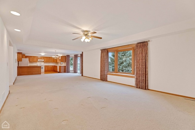 unfurnished living room with ceiling fan with notable chandelier and light colored carpet