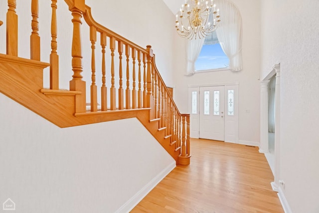 entrance foyer featuring hardwood / wood-style floors, a towering ceiling, and a chandelier