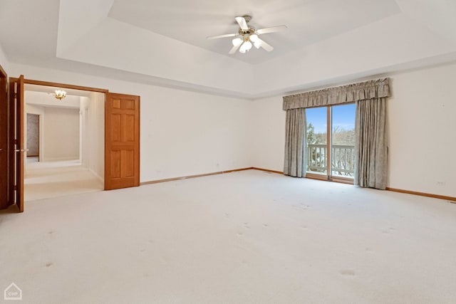 carpeted spare room with a raised ceiling and ceiling fan with notable chandelier