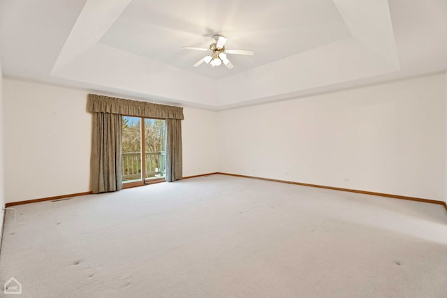 unfurnished room with a raised ceiling, carpet, and ceiling fan