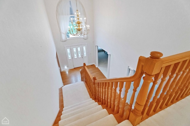 staircase with hardwood / wood-style floors, a chandelier, and a high ceiling