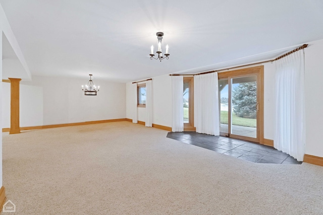 carpeted empty room with a healthy amount of sunlight and a chandelier