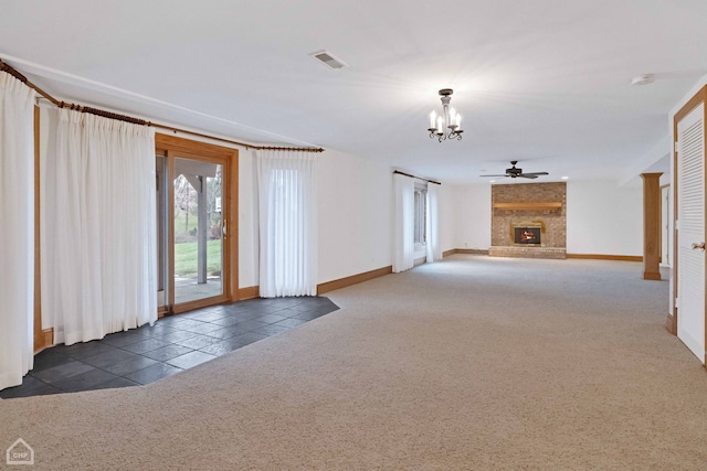 unfurnished living room with a brick fireplace, ceiling fan with notable chandelier, and dark colored carpet