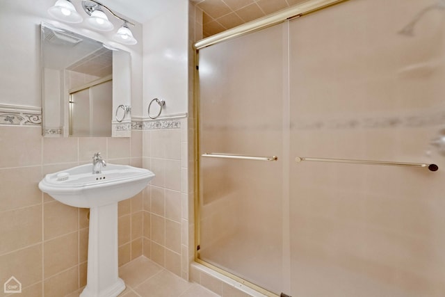 bathroom featuring a shower with door and tile walls